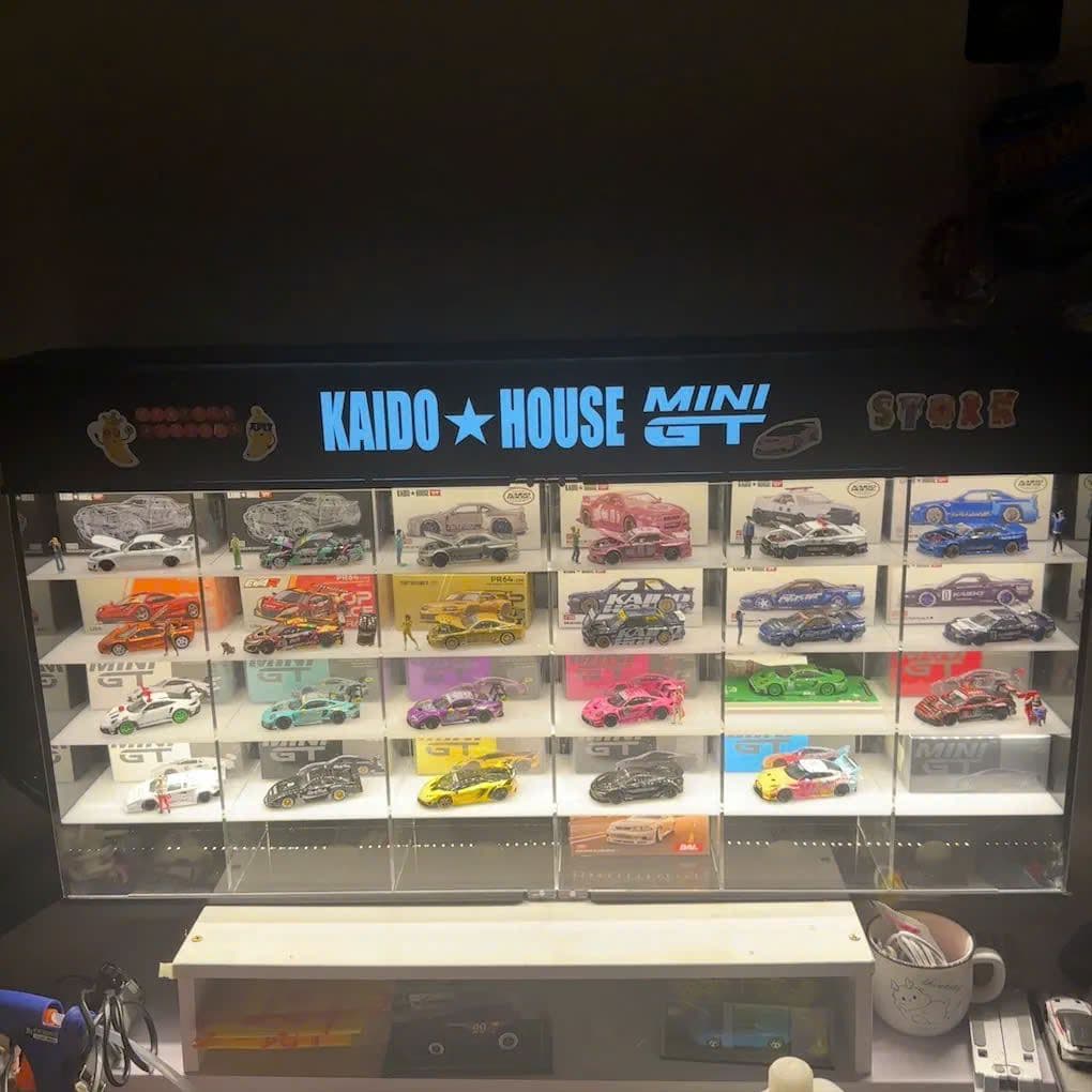 Kệ đèn trưng bày Kaido House × Mini GT xếp các hộp mô hình 1:64, bật đèn trong phòng tối