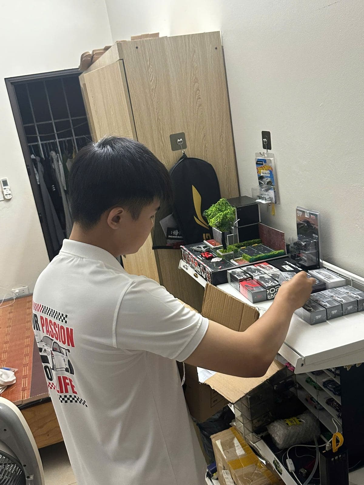 Thành viên Sentock mặc áo Your Passion Your Life đóng gói hộp mô hình tại bàn làm việc