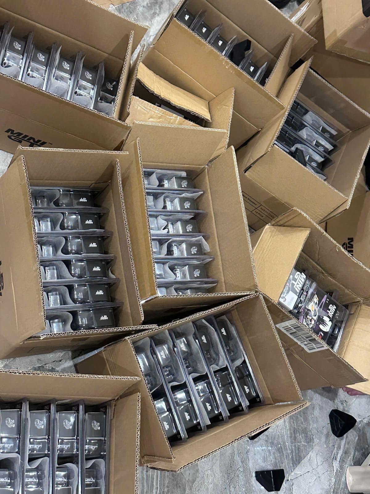 Nhiều thùng carton xếp đầy hộp Mini GT, chụp từ trên xuống